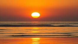 golden HuaHin sunset, mesmerizing, reflections on beachfront water, photorealistic, contrasting shadows stretching, highly detailed, horizon glow, balanced exposure, gold and purple spectrum, soft shadow, shot with a wide-angle lens.